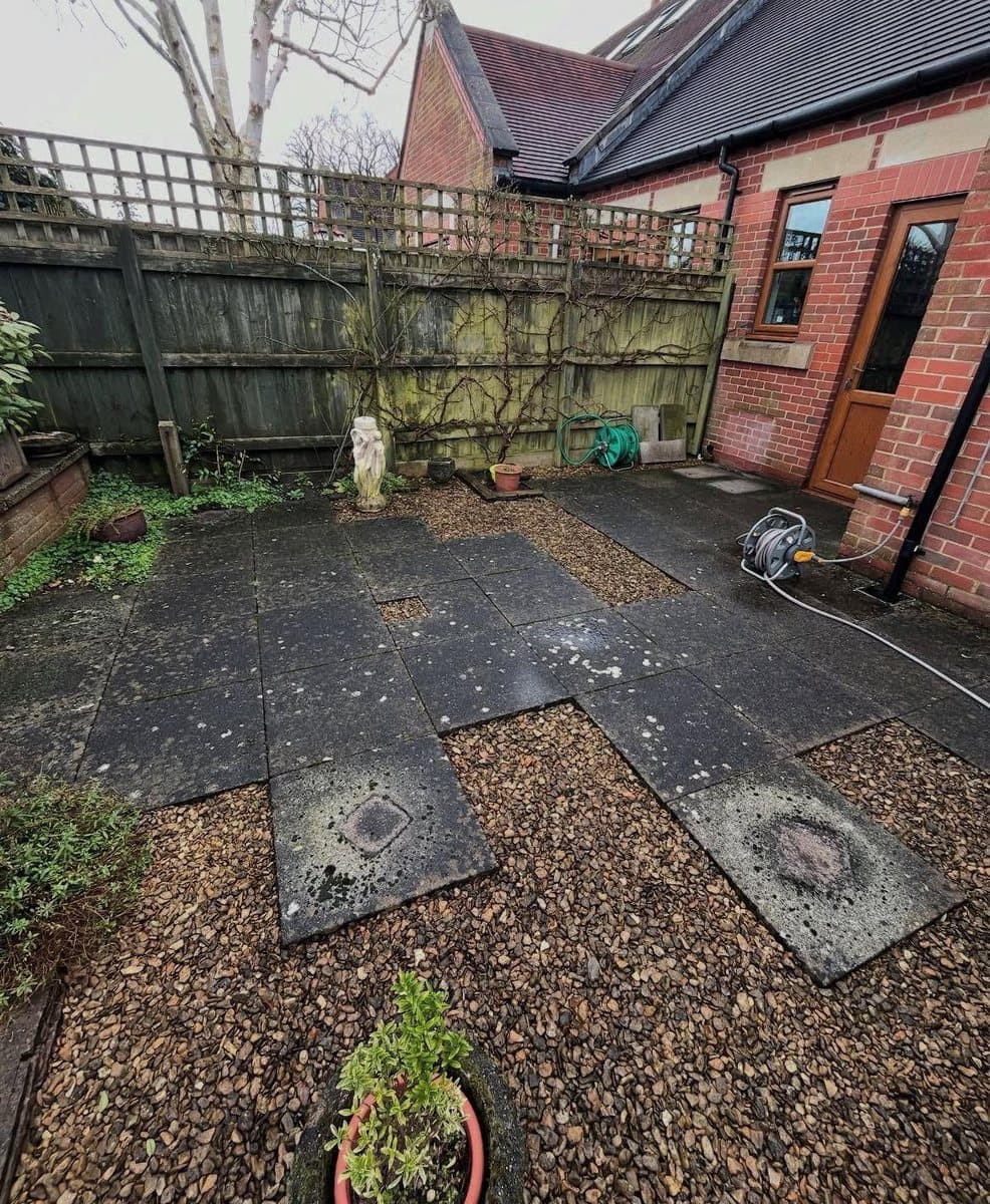 Garden patio before a jet wash, slabs dark with moss and algae staining